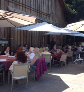 People sitting on the patio of the tasting room at tables under umbrellas